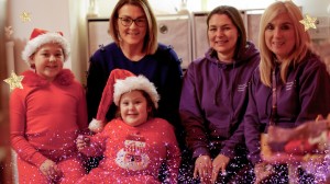 christmas theme image of a family sat smiling together with 2 support workers from SBH Scotland