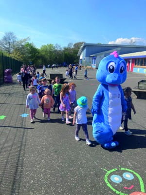 SBH Scotland's mascot Spiney the Diney leads a group of children across a playground for a sponsored walk