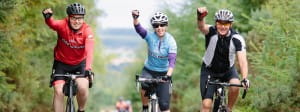 3 cyclists with hand in air to celebrate