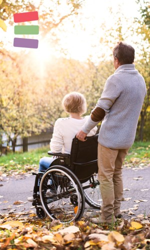 Man stood holding lady in a wheelchair looking into sunset